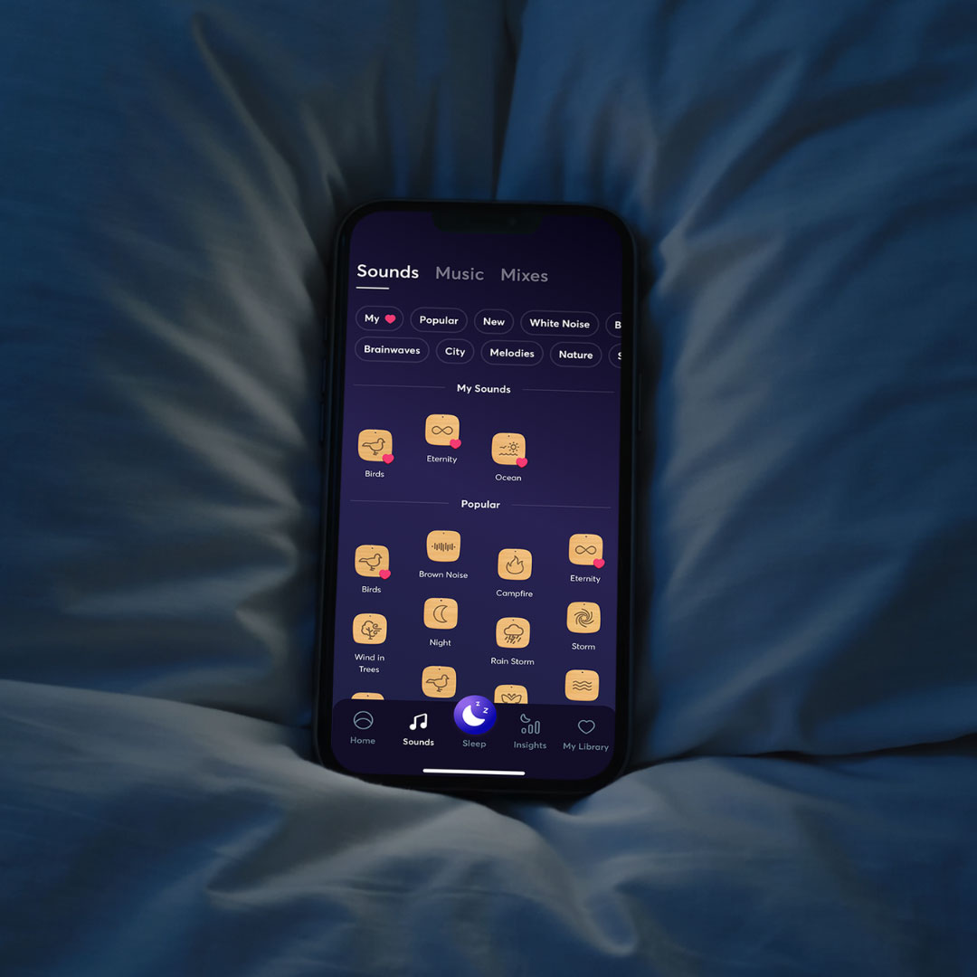 BetterSleep app sound library shown on a phone beside pillows