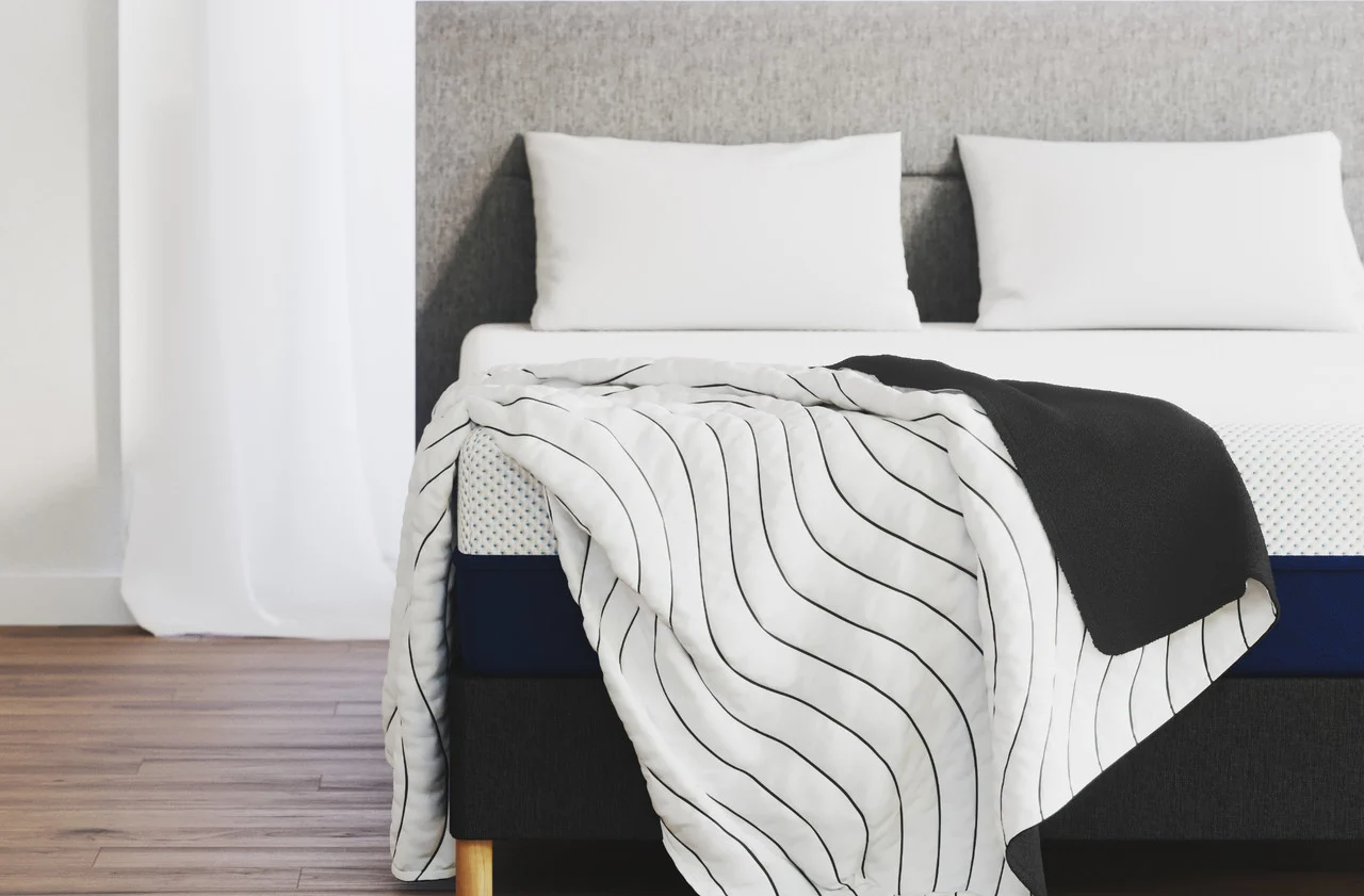 Amerisleep Allseasons Blanket shown on a bed with its black fleece and white Chill fabric sides